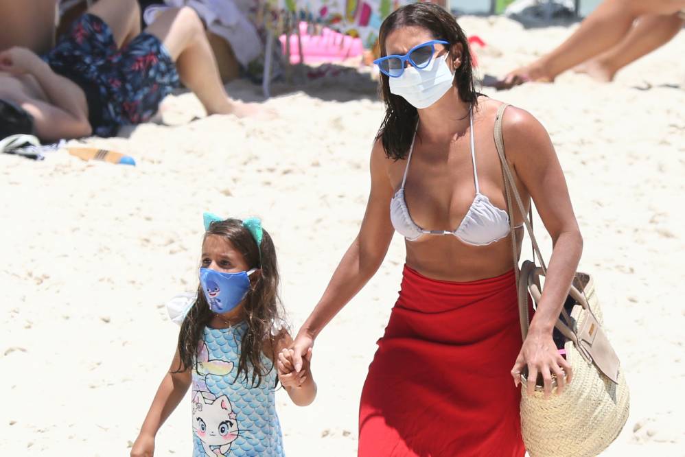 Deborah Secco caminha pela praia com a filha na Barra da Tijuca, ambas de máscara