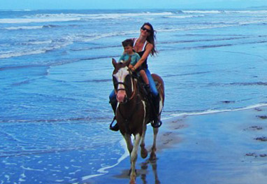 Gisele Bündchen cavalga com o filho na praia