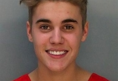 Justin Bieber sorrindo com roupa laranja de presidiário