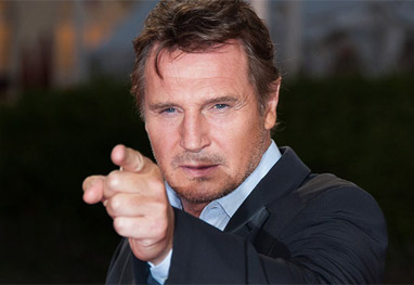 Liam Neeson apontando o dedo para a câmera