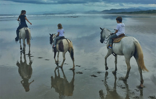 Gisele Bündchen em passeio a cavalo na praia com os filhos