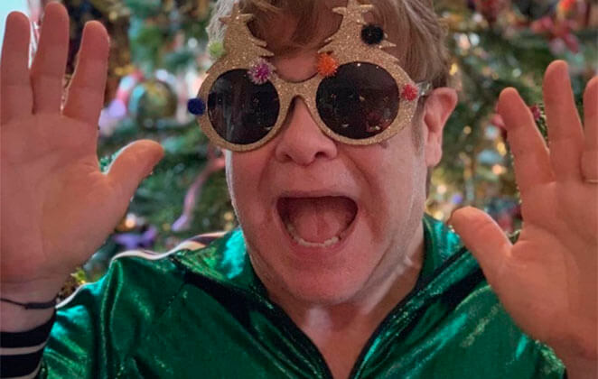 Elton John com óculos extravagante e roupa verde