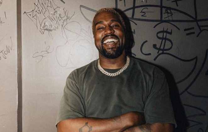 Kanye West sorri em foto contra a parede