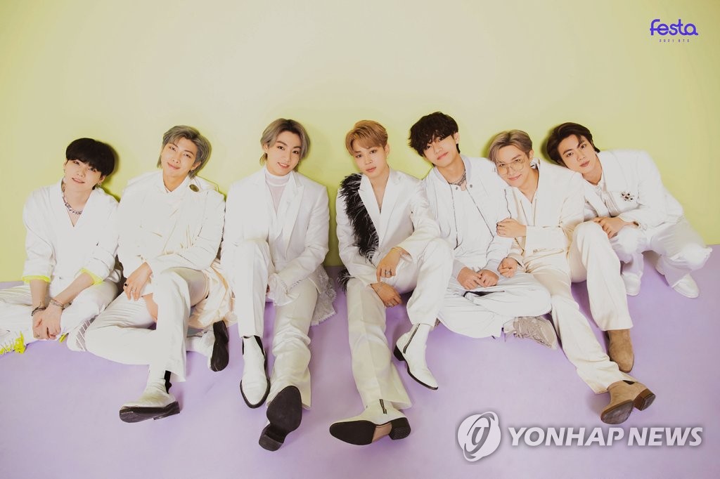 BTS em foto onde estão sentados lado a lado com um fundo colorido