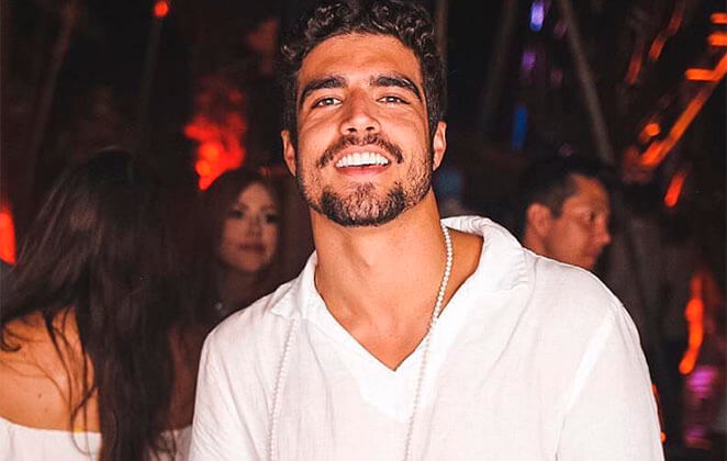 Caio Castro sorridente usando blusa branca