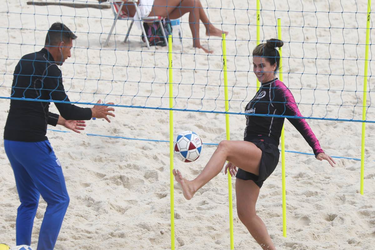 giovanna antonelli pratica futevôlei com personal trainer na praia, chutando uma bola próxima da rede