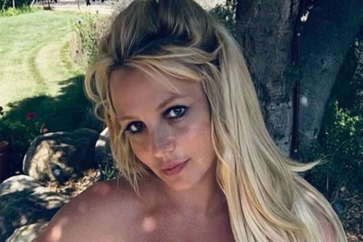 Britney Spears aparece em close generoso, de cabelos soltos, embaixo de uma árvore