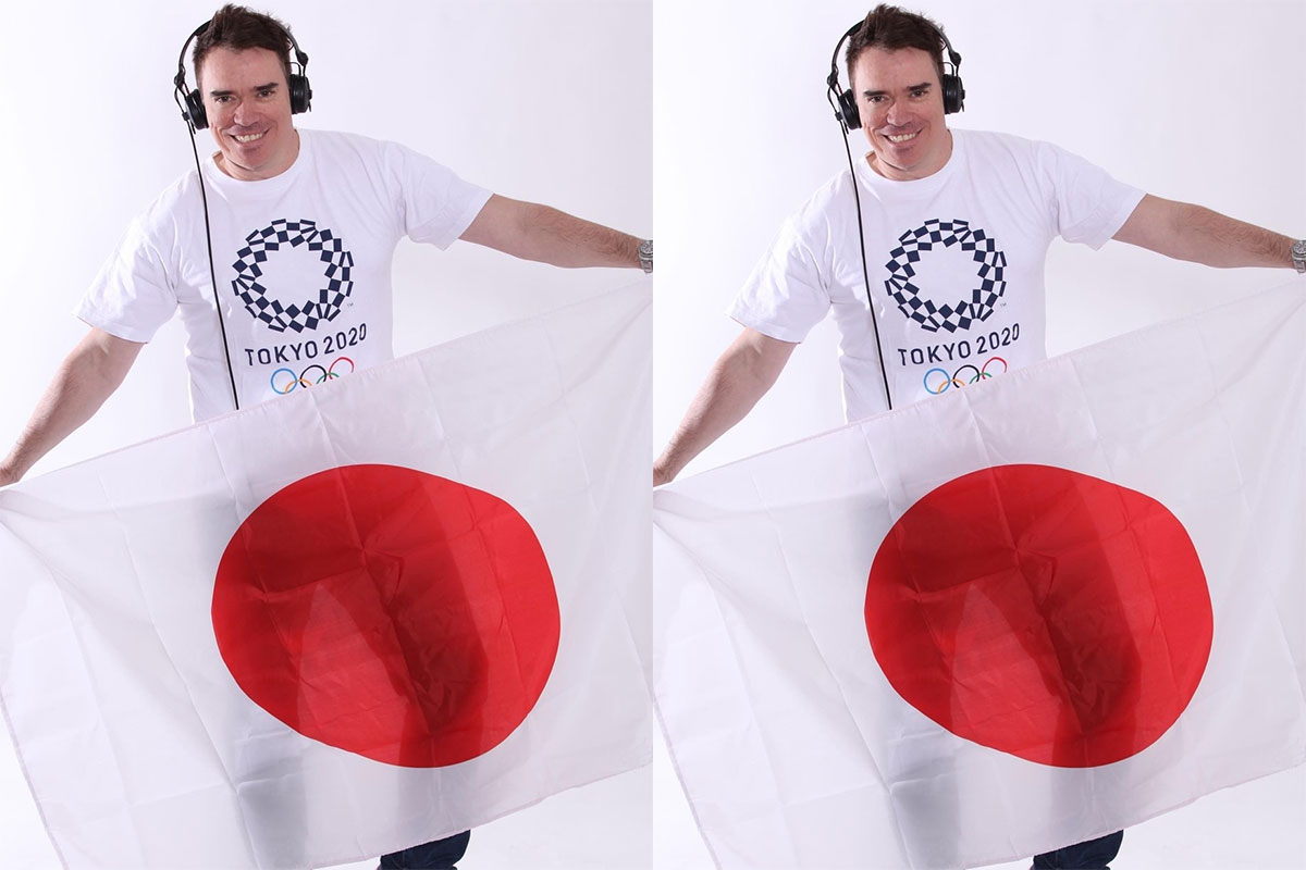 DJ Stari, de camiseta com a logomarca da Olimpíada, usa fone e segura a bandeira do Japão