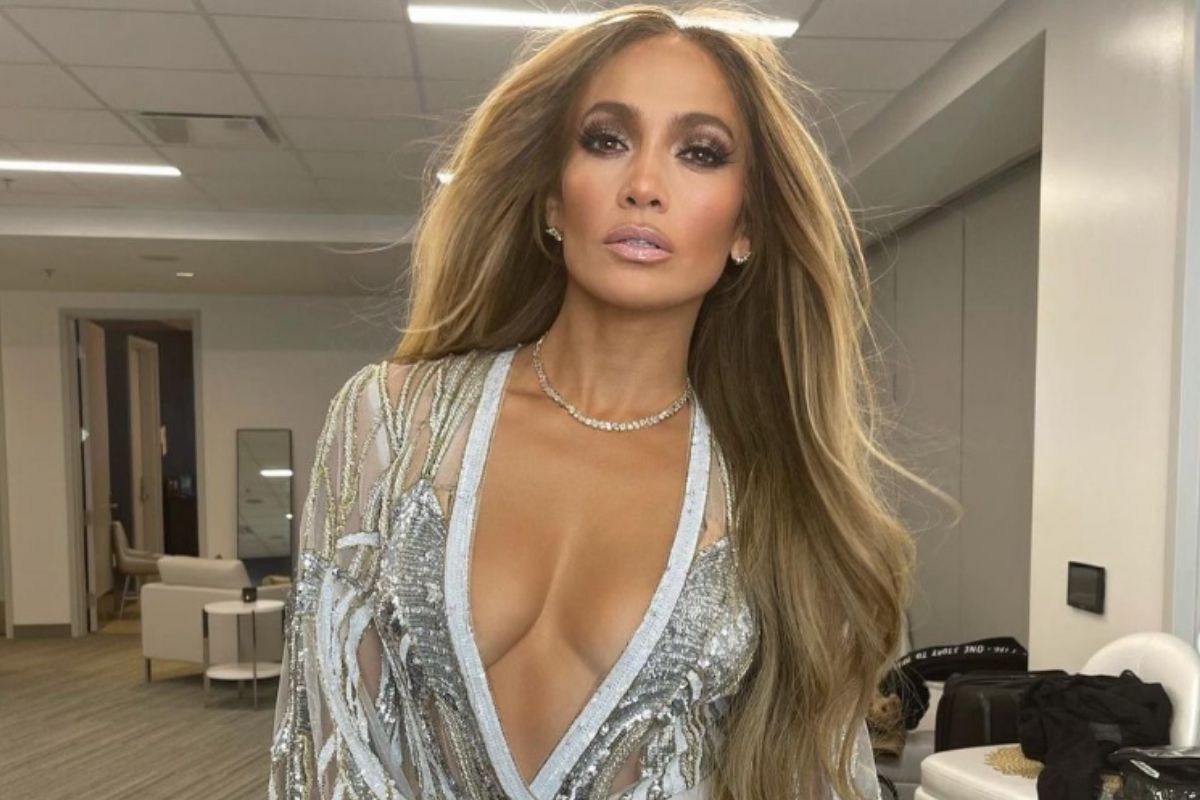 Retrato de Jennifer Lopez maquiada, com roupa branca e cabelos soltos