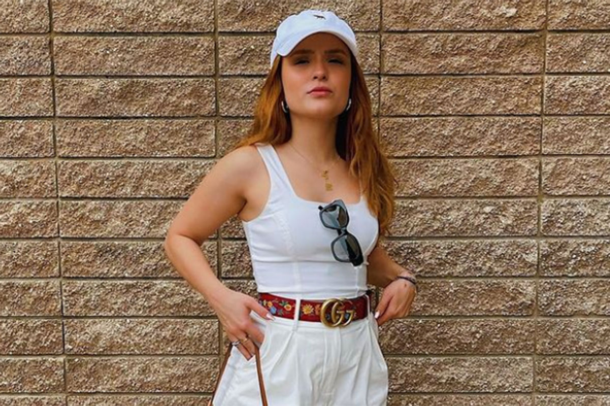 Larissa Manoela com roupa e boné branco, fazendo cara de séria, na Disney