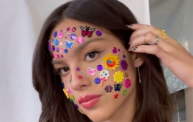 Olivia Rodrigo com adesivos coloridos no rosto