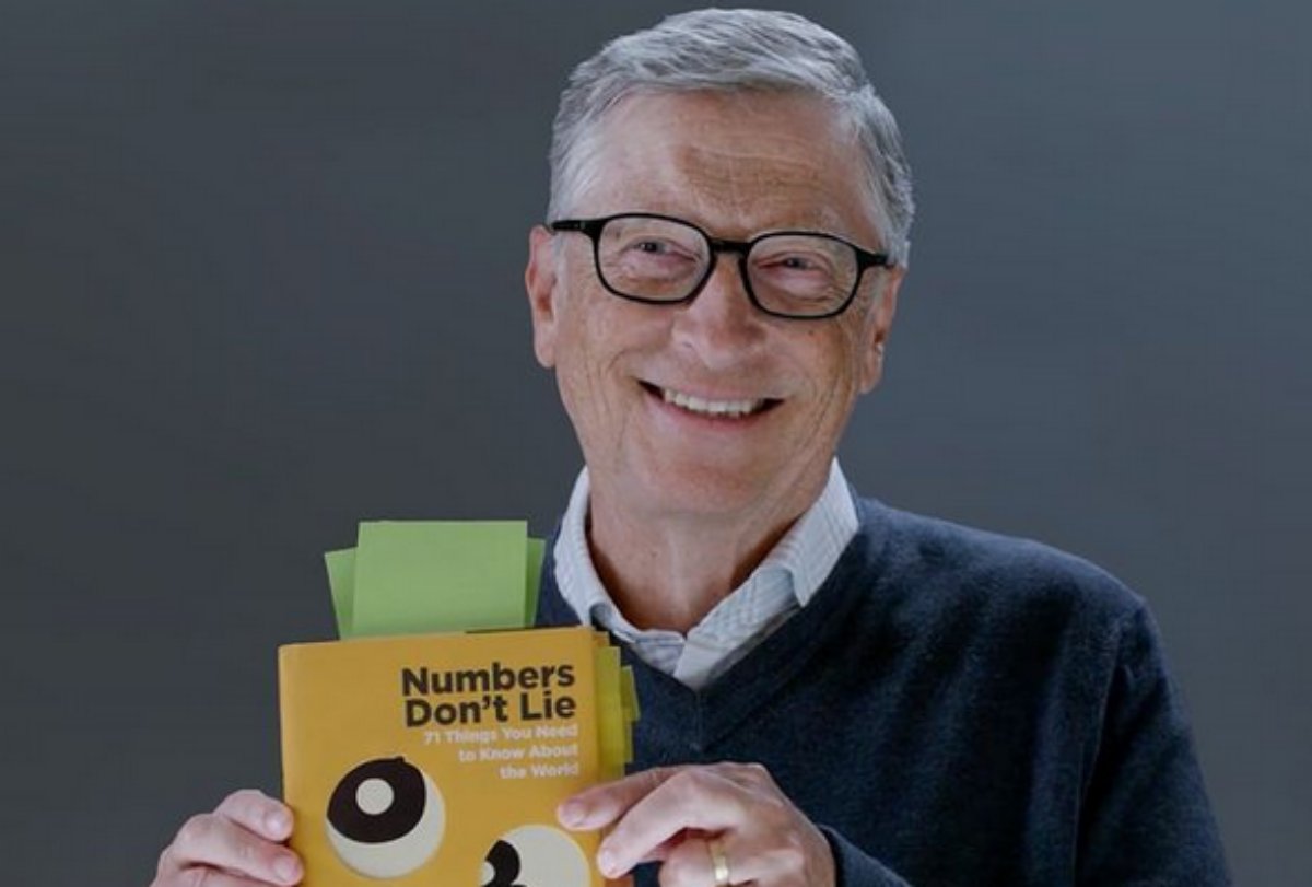 Bill Gates sorri segurando um livro