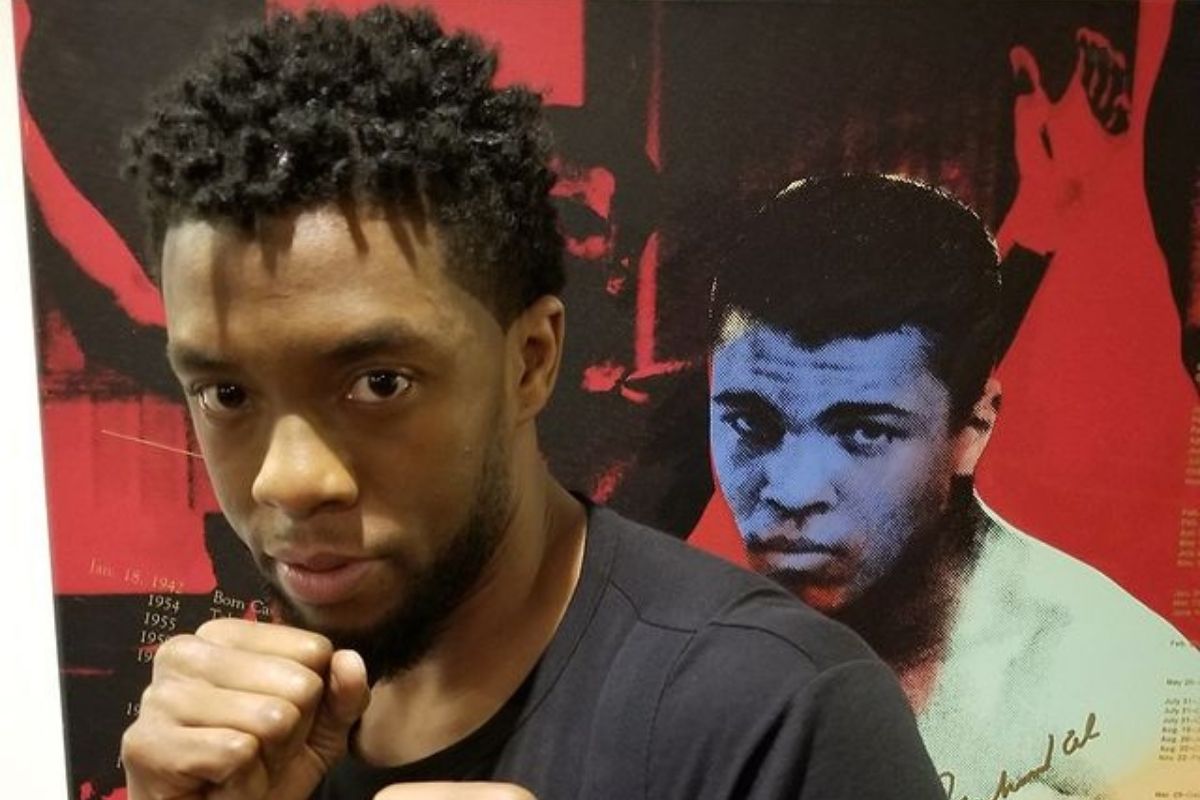 Chadwick Boseman em foto com a imagem do Muhammad Ali atrás