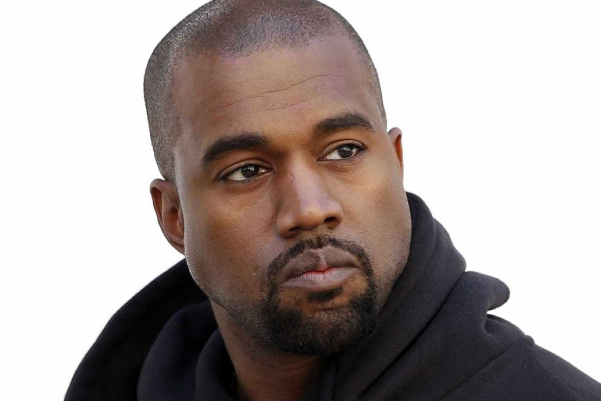 Foto de Kanye West sério, vestindo um casaco de moletom preto e o fundo da imagem branco