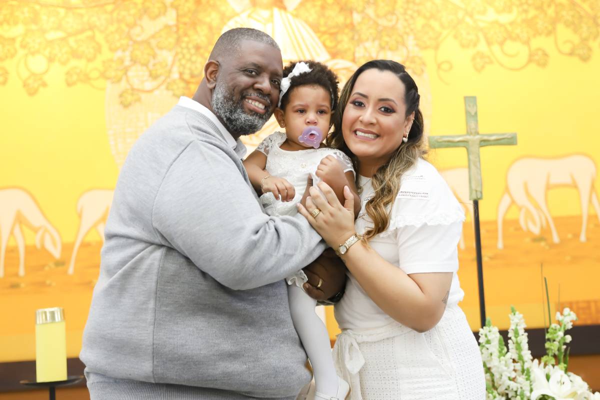 péricles e lidiane abraçados com a filha maria helena no colo em batizado dela