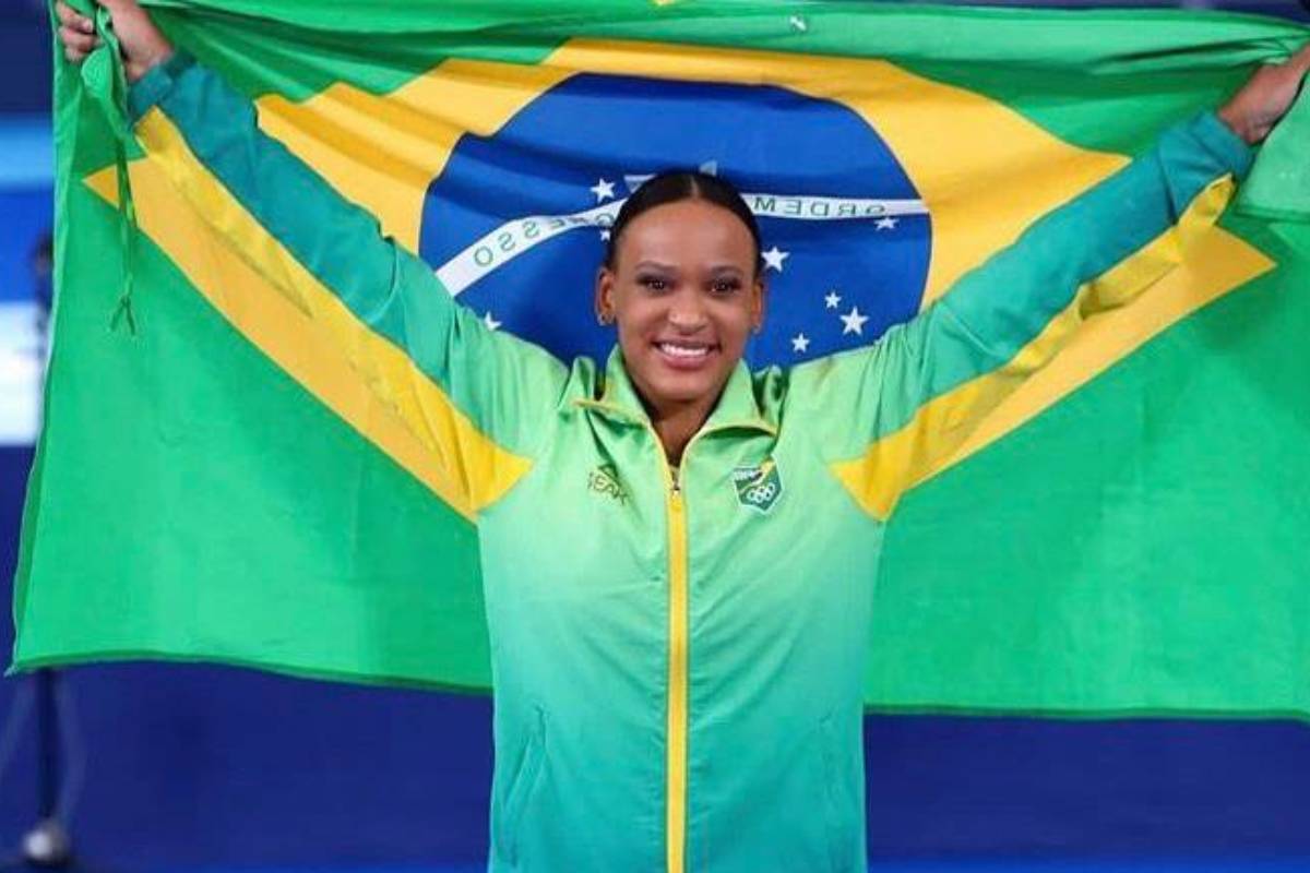 rebeca andrade com a bandeira do brasil em pódio de tóquio