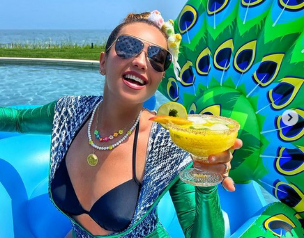 Thalía posa na piscina com uma bebida na mão