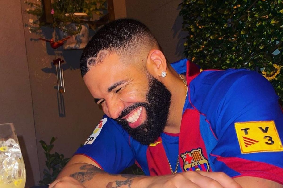 Foto de Drake rindo enquanto toma um drink