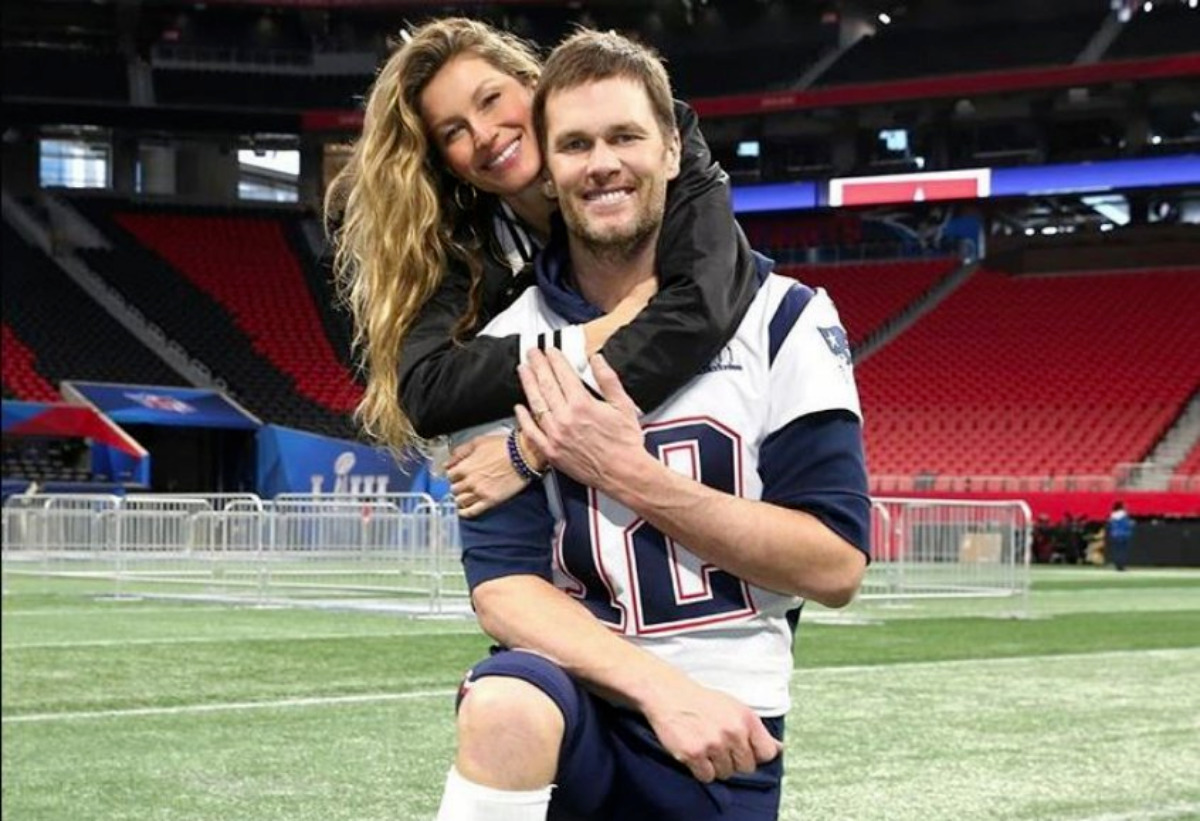 Gisele Bundchen abraçada ao marido, Tom Brady, no campo de futebol americano