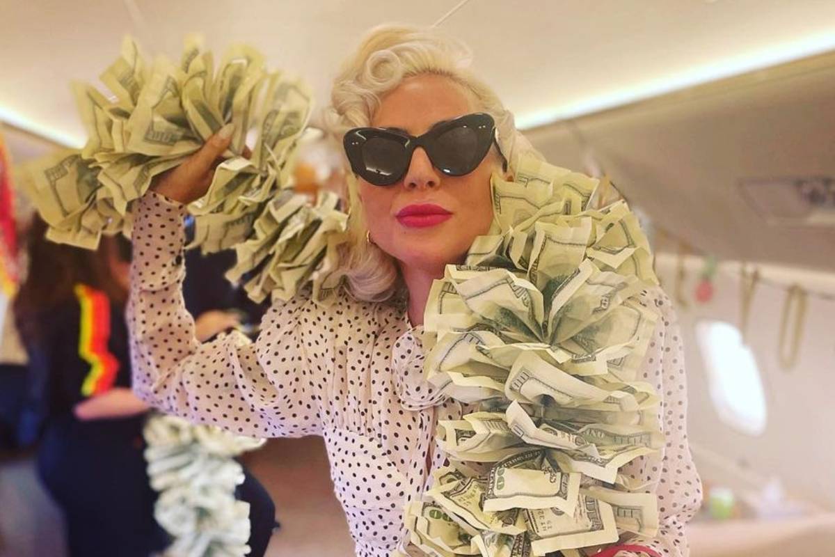 lady gaga posando enquanto ostenta um cachecol de dólares enrolado no corpo