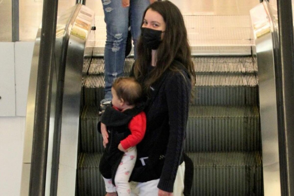 Nathalia Dill com a filha no colo, na escada rolante do shopping