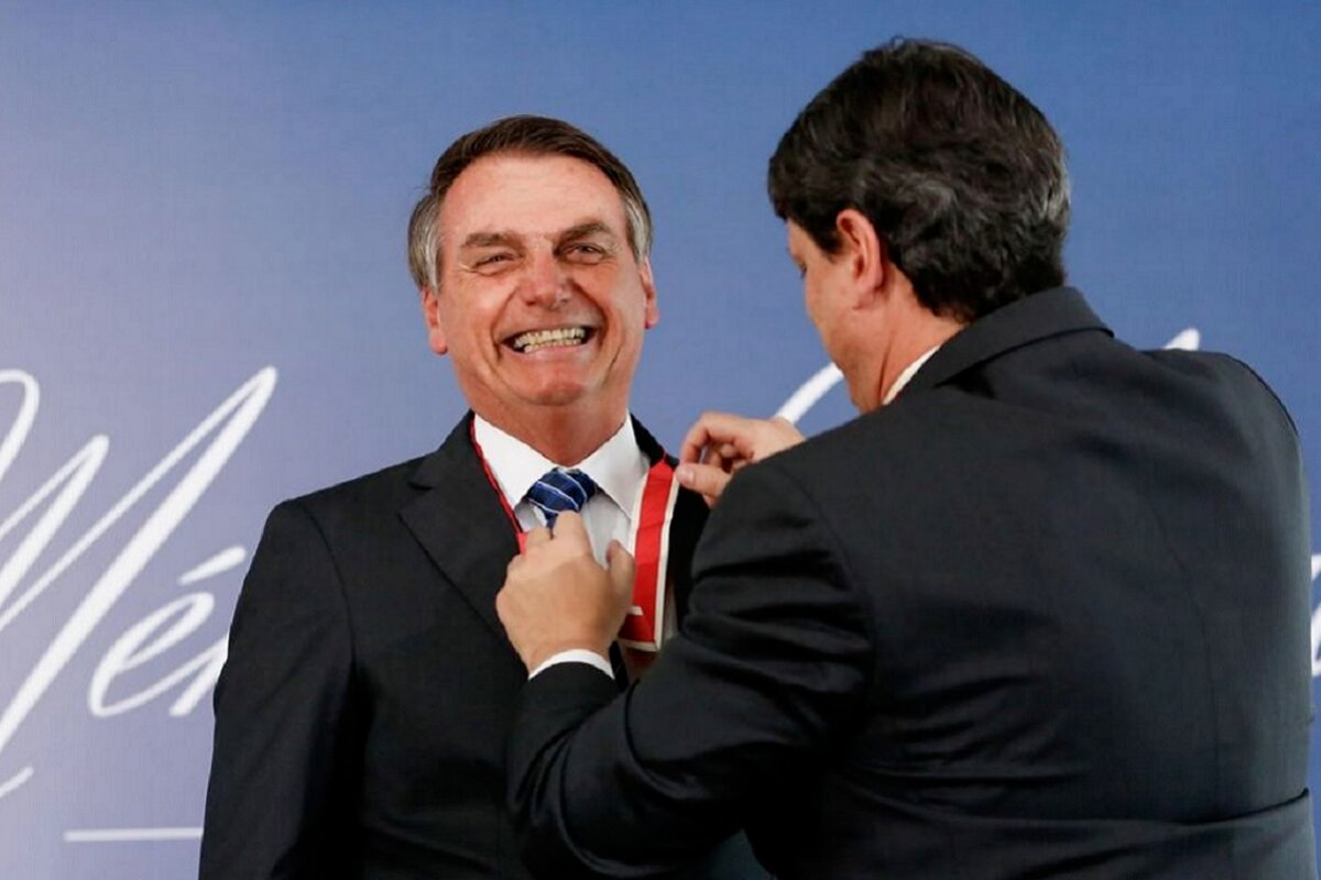 Jair Bolsonaro sorrindo ao receber medalha