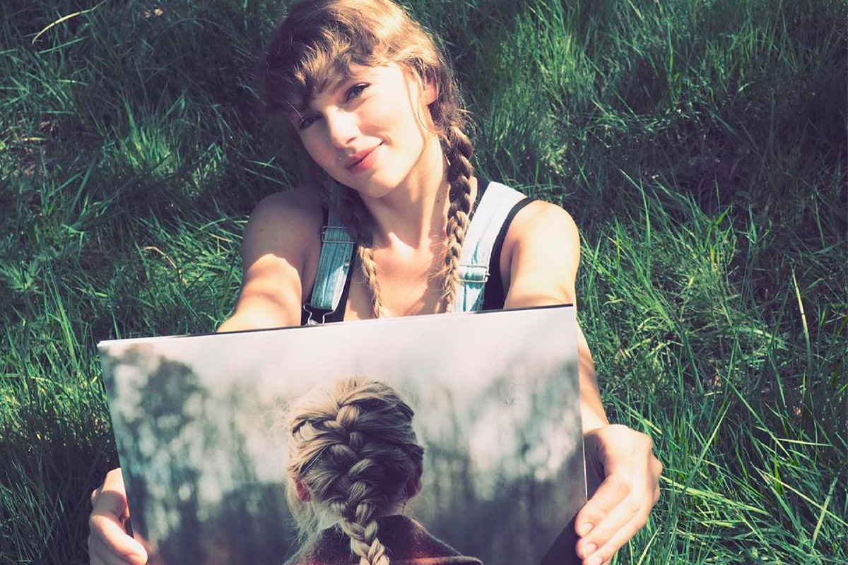 Taylor Swift posando para foto com álbum de vinil "evermore".