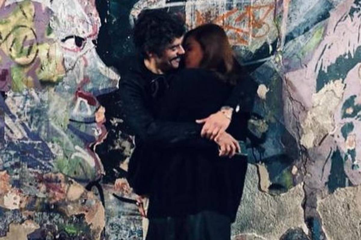 titi muller e gentil fernandes se beijando em frente a parede grafitada