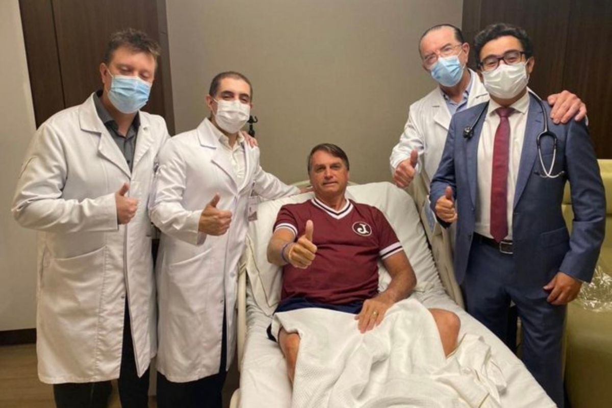 Jair Bolsonaro em quarto de hospital com médico em sua volta
