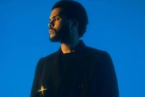 the weeknd posando sério com look preto em um fundo azul