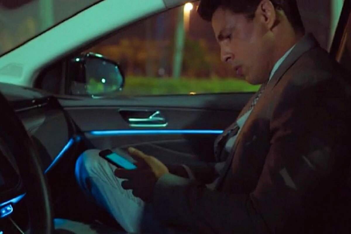 Christian (Cauã Reymond) no carro, olhando o telefone