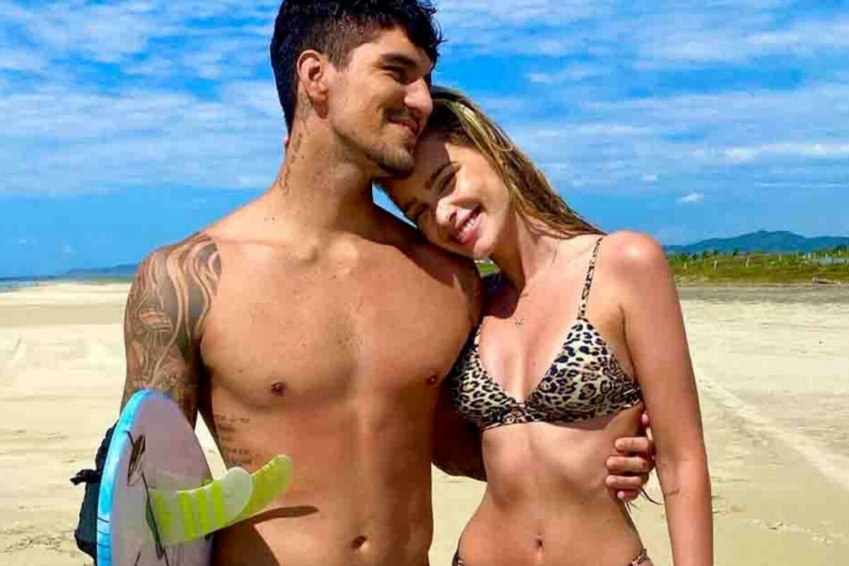 Gabriel Medina e Yasmin Brunet abraçados, na praia, ele segurando uma prancha