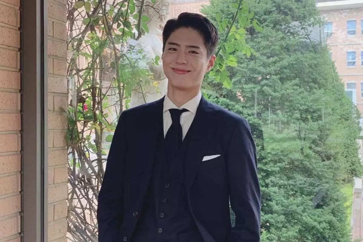 Park Go Bum em foto sorrindo, usando terno
