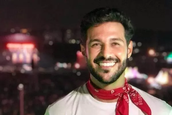 Rodrigo Mussi sorrindo, de bandana no pescoço e camisa branca