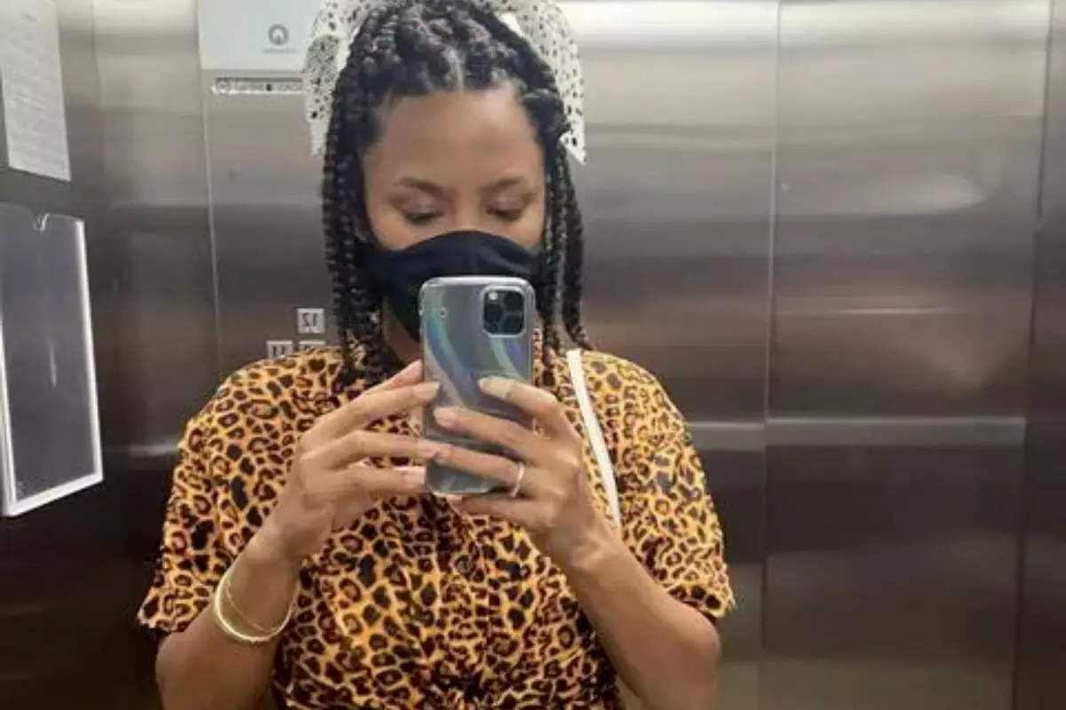 Jessica Ellen de máscara preta, fazendo selfie no elevador