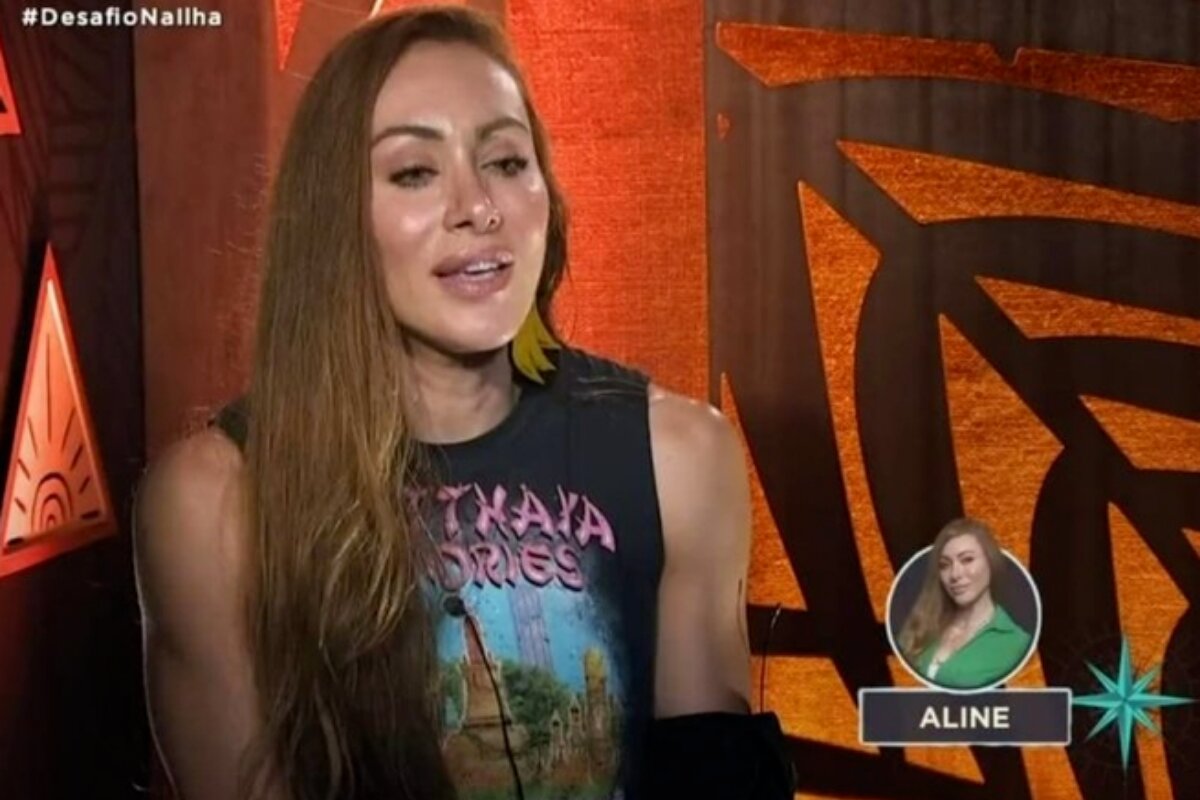 Aline Dahlen de camiseta preta estampada, na cabine de entrevistas do "Ilha Record"