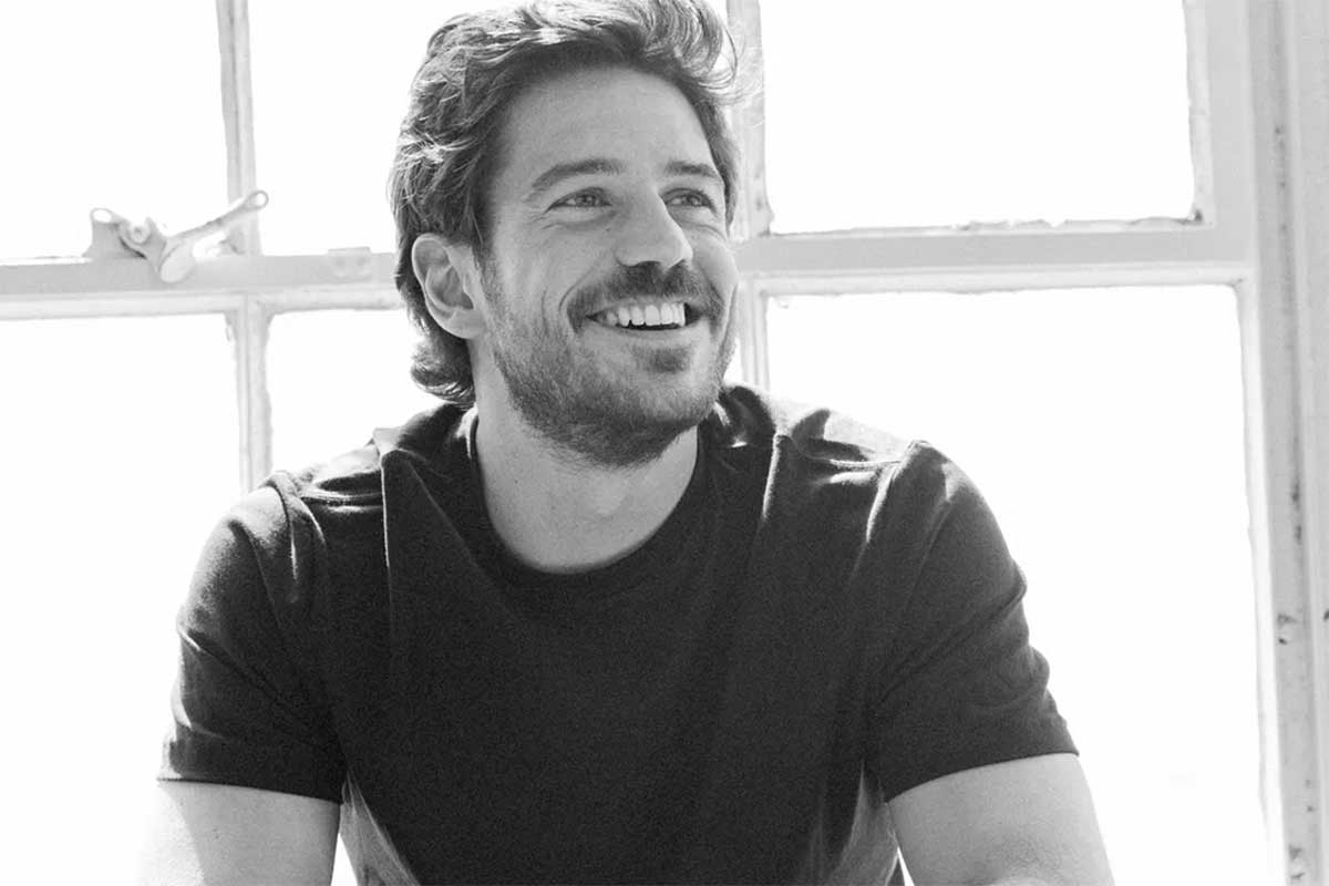 Foto em preto e branco do ator Marco Pigossi, sorrindo
