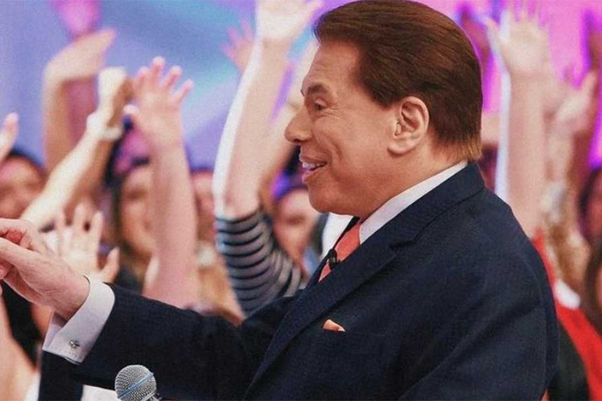 Silvio Santos, de perfil, sorrindo na plateia do seu programa