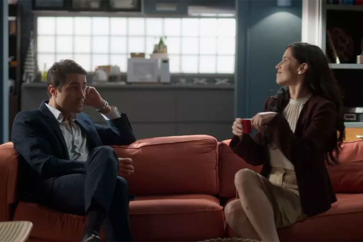 Danilo (Ricardo Pereira) e Regina (Mel Lisboa) sentados no sofá, em cena de Cara e Coragem