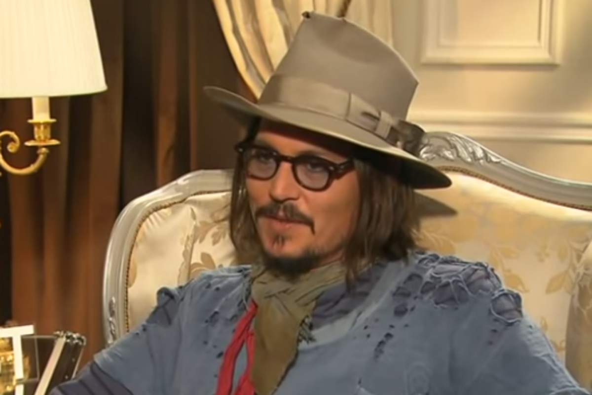 Johnny Depp, de chapéu, sentado em entrevista