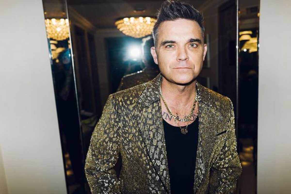 Robbie Williams de casaco e olhar sério