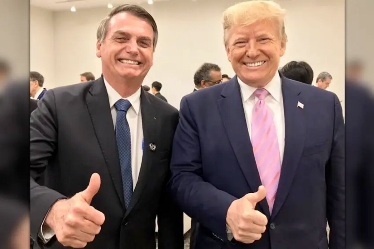 Jair Bolsonaro ao lado de Donald Trump ambos de terno, fazendo sinal de positivo e sorrindo
