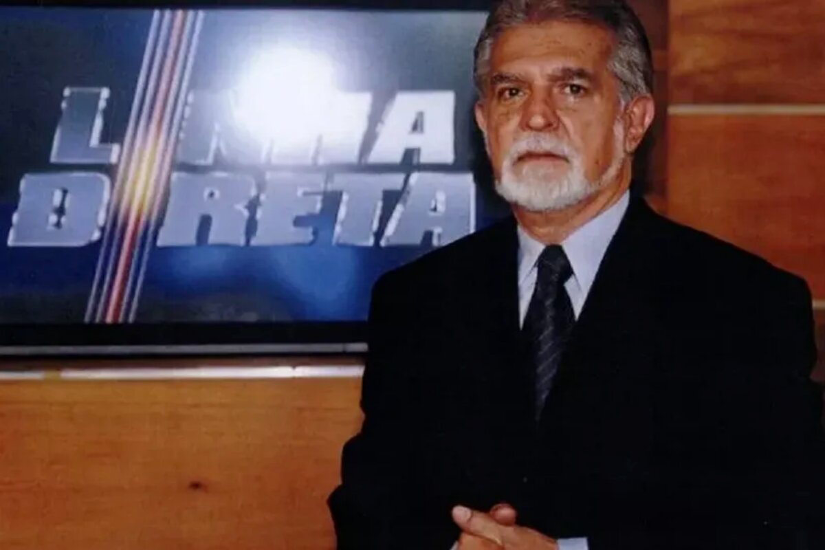 Domingos Meirelles, de terno e gravata, posado na logo do programa 'Linha Direta'