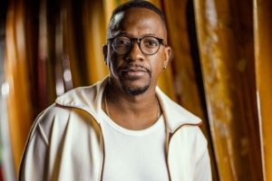 mumuzinho posando com look branco em ambiente com madeiras