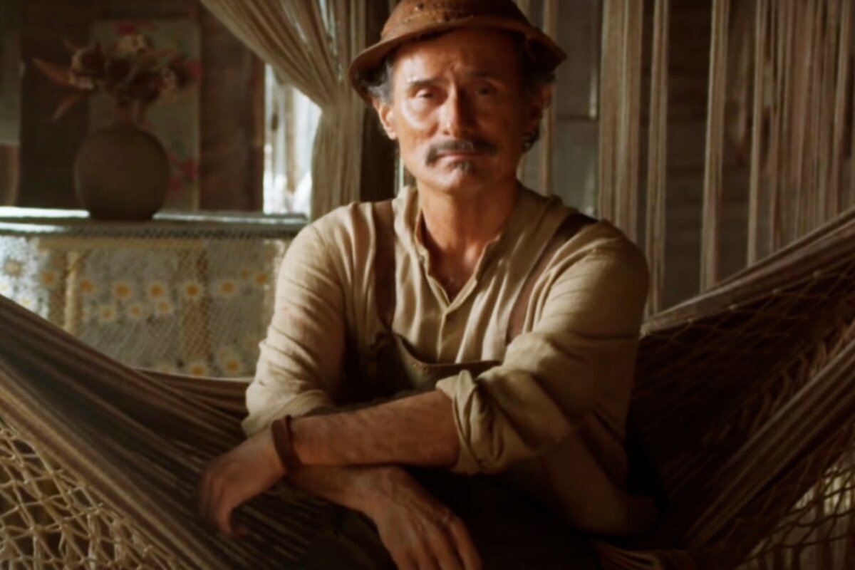 Timbó (Enrique Diaz) sentado na rede, de chapéu de cangaceiro, em cena de Mar do Sertão