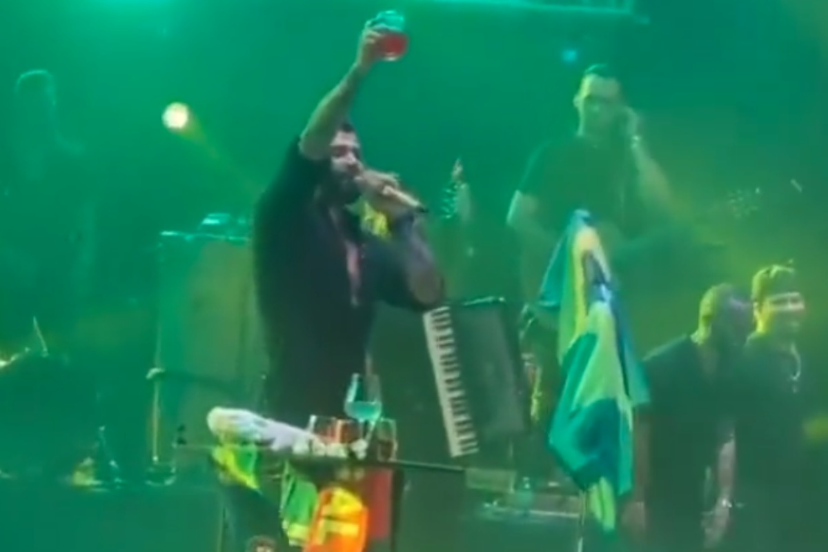 gusttavo lima levantando drink com bandeira do brasil no palco durante show em miami