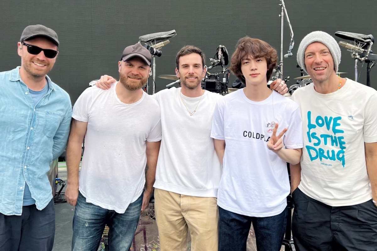Jin, do BTS, e integrantes do Coldplay posando para foto
