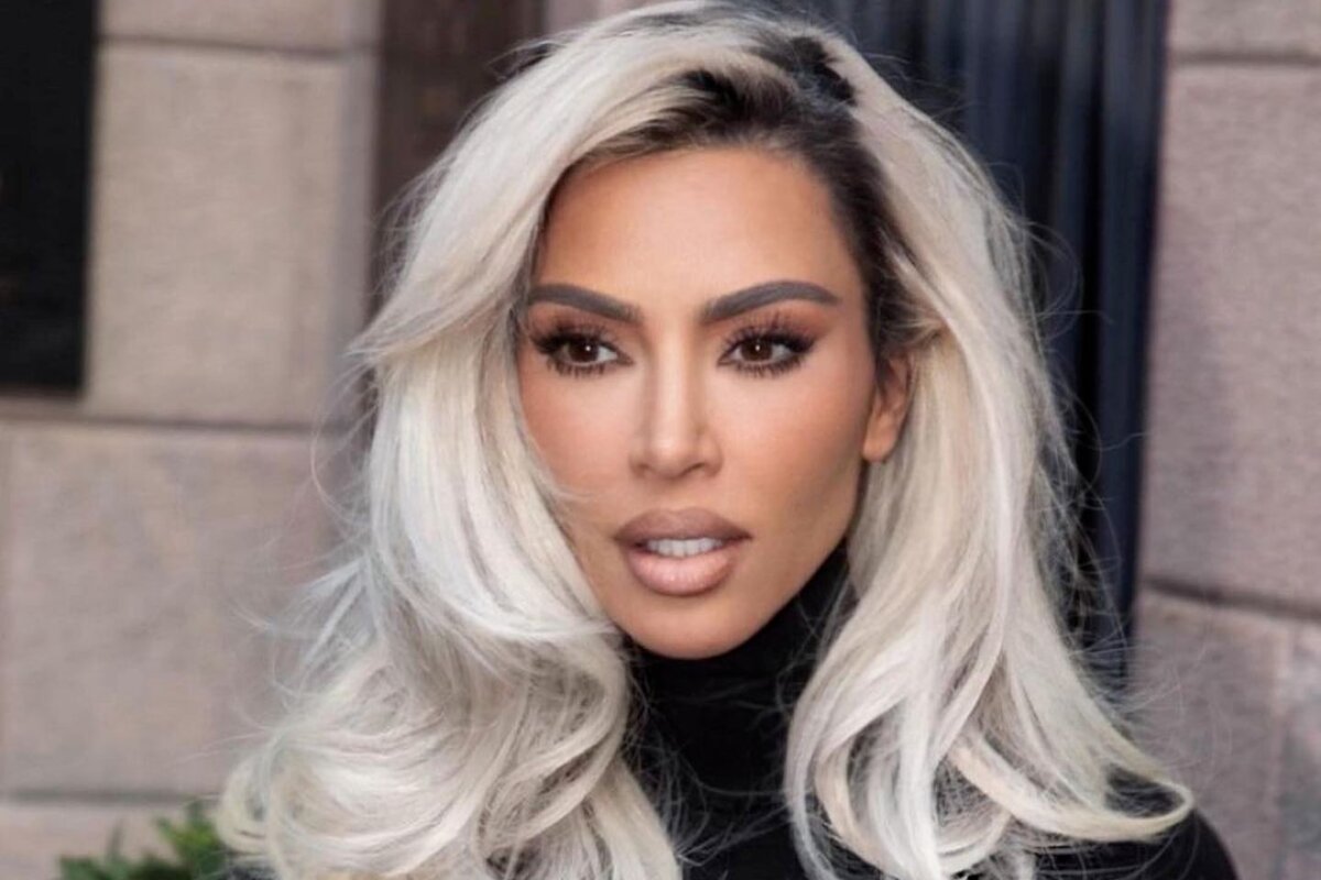 Kim Kardashian loira, cabelos soltos, camisa de gola alta preta