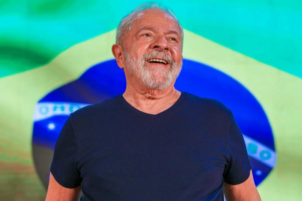 Lula de camisa preta, diante da bandeira do Brasil