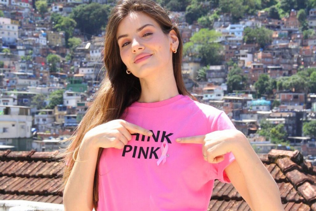 Camila Queiroz de camisa outubro rosa, calça preta com as mãos no bolso